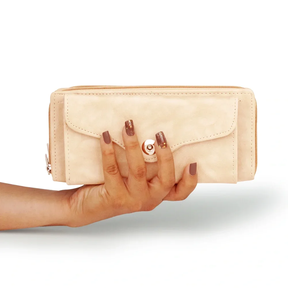 a hand holding a tan purse