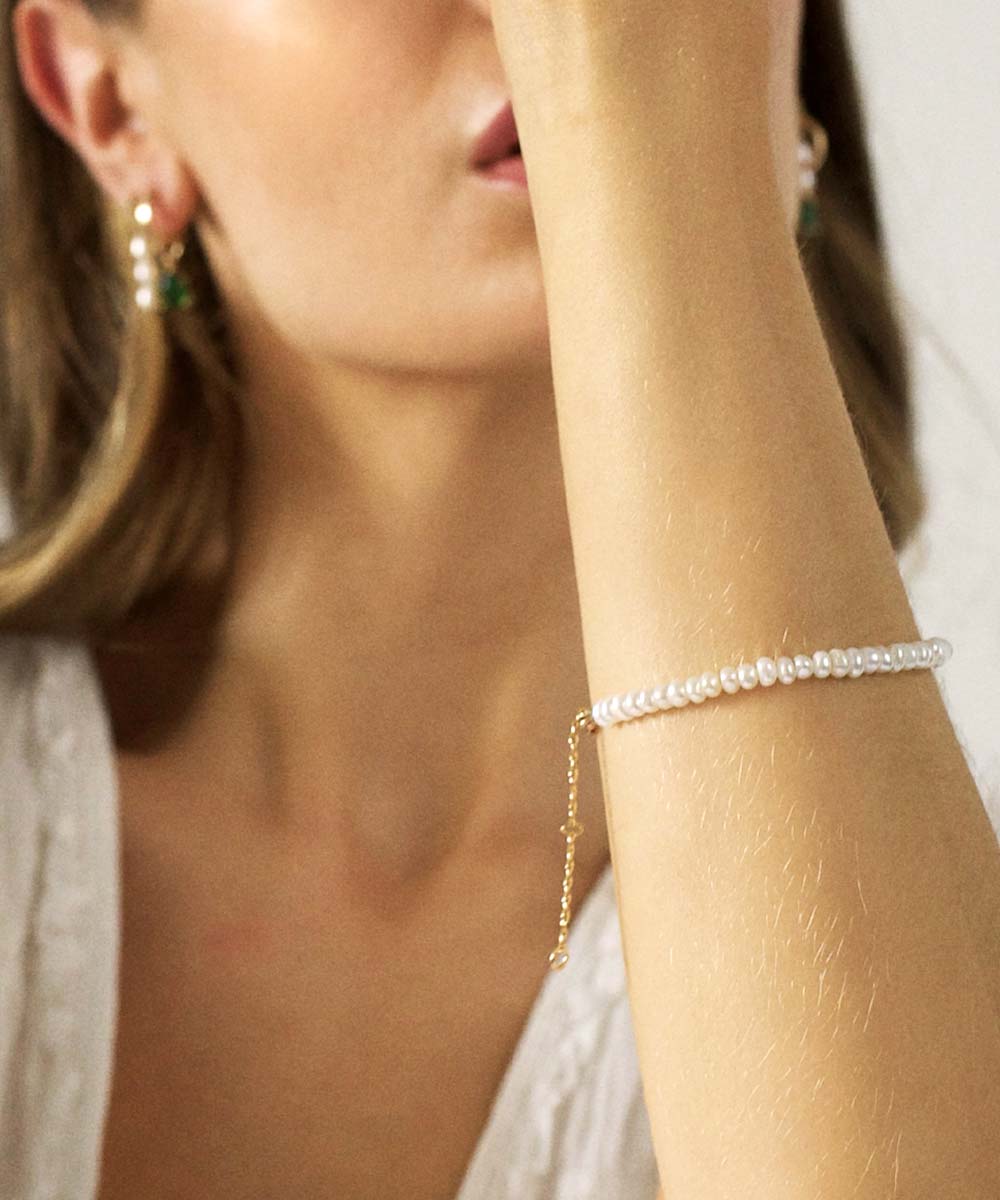 a woman wearing a pearl bracelet and earrings