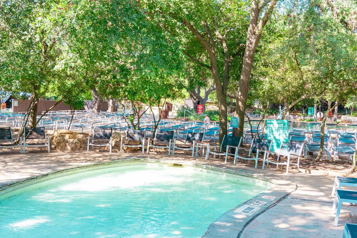 a pool with chairs and trees