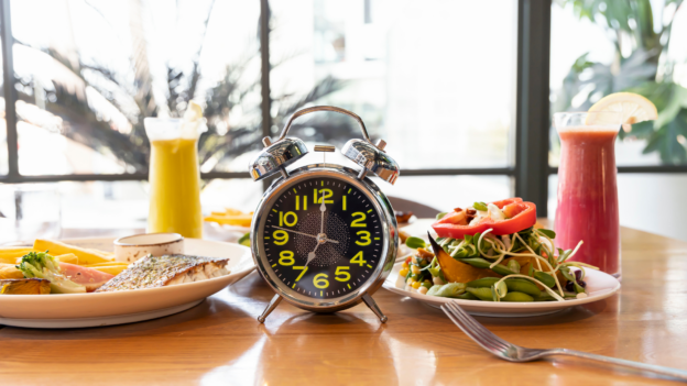 a clock on a table with food on it