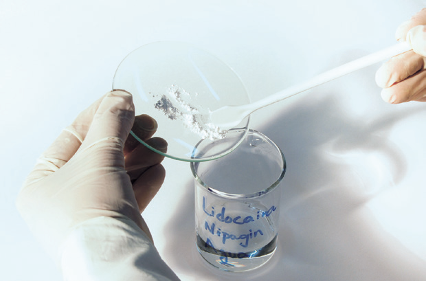 a hand holding a spoon over a glass