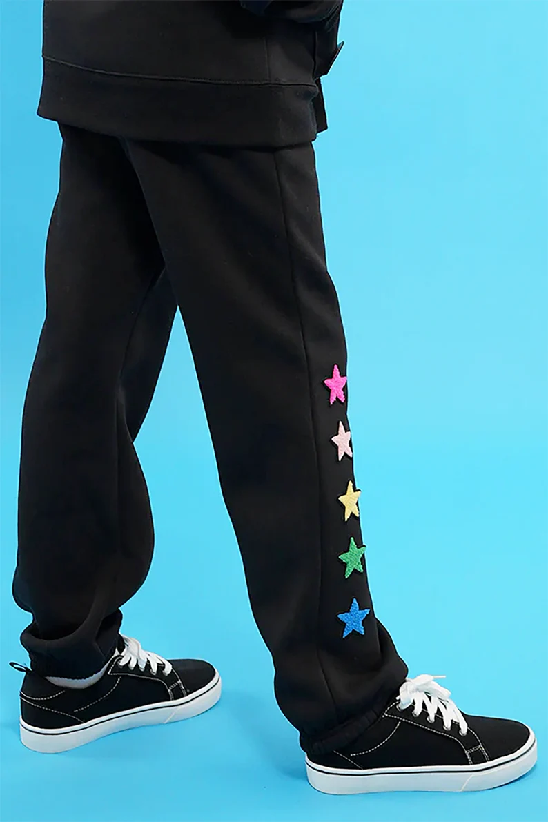 a person wearing black pants with colorful stars on side