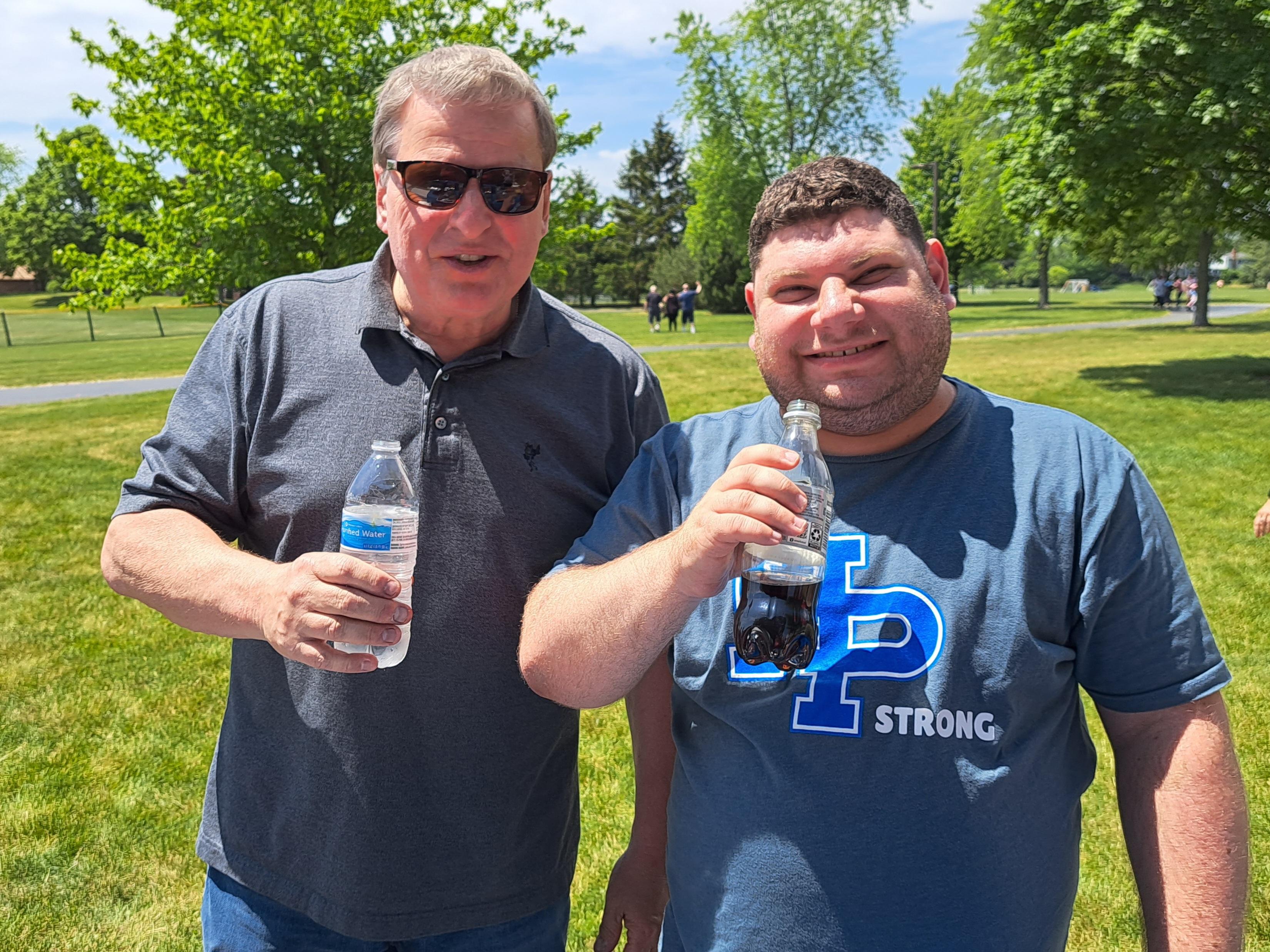 two men holding bottles of soda