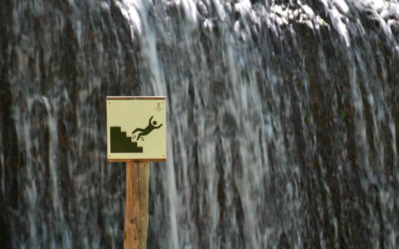 a sign on a post next to a waterfall