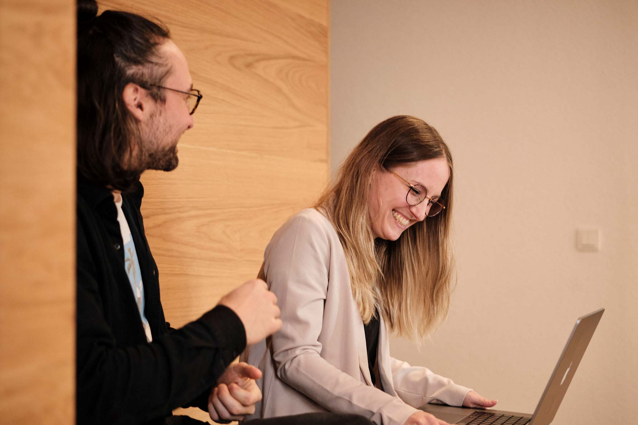a man and woman laughing at a laptop