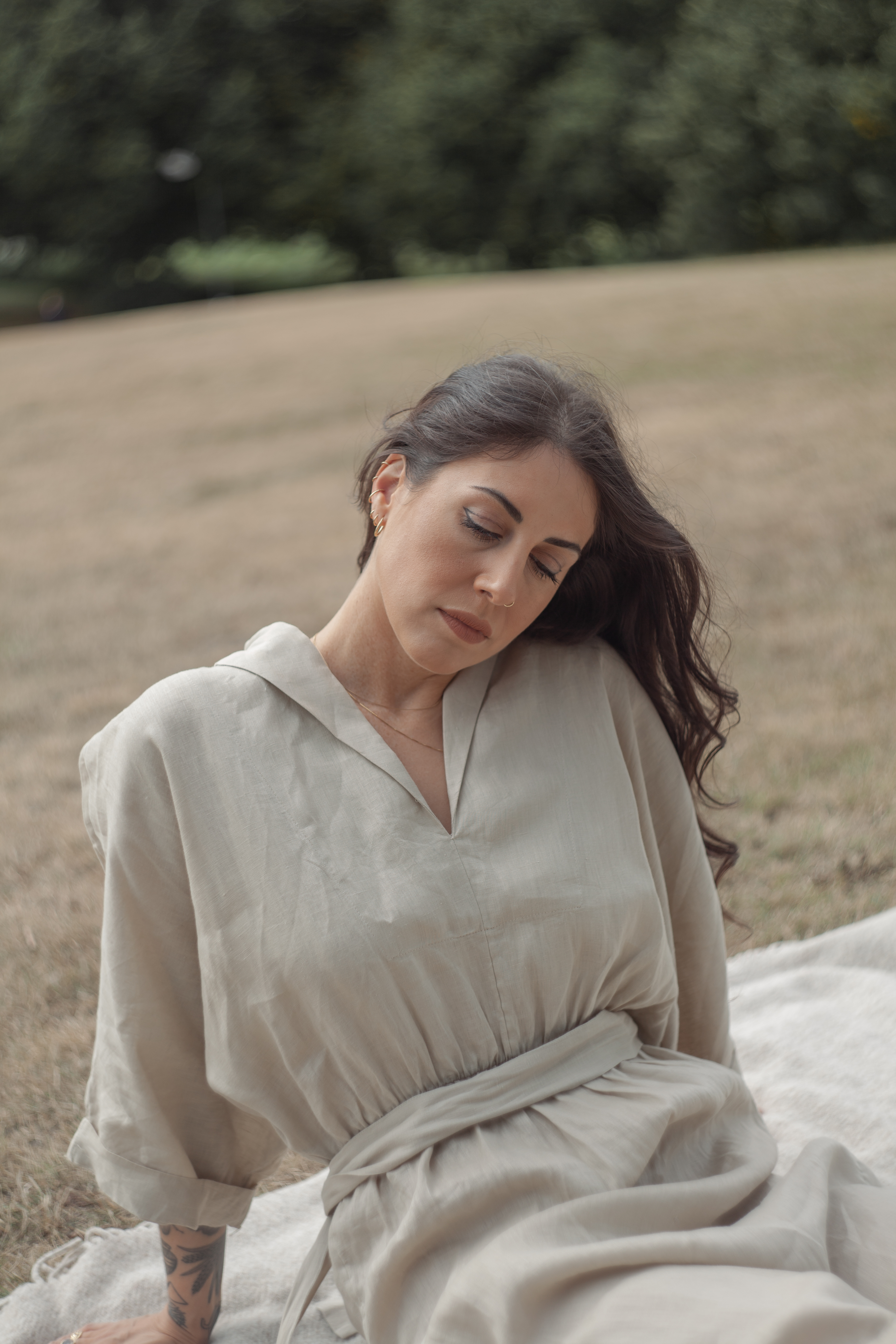 a woman sitting on a blanket in a field