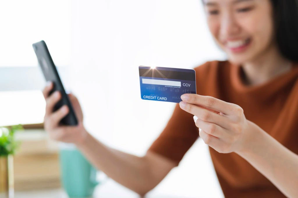 a woman holding a credit card and a phone
