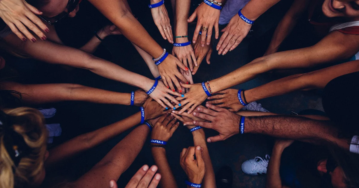 a group of hands with blue bracelets