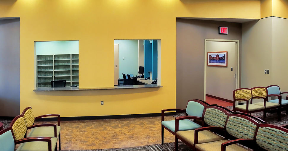 a yellow wall with chairs and a desk