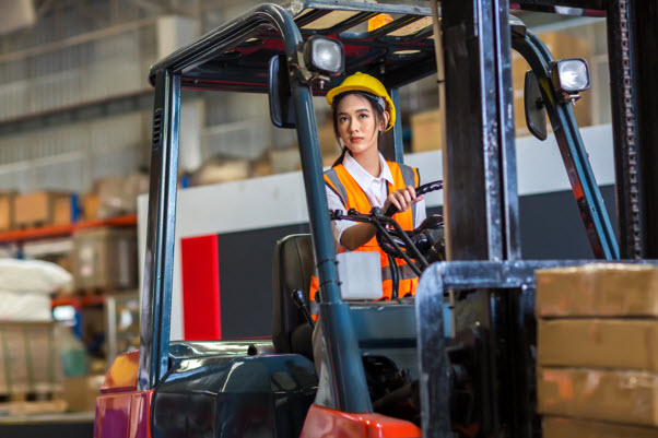a woman in a hard hat driving a forklift