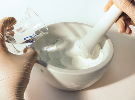 a person pouring white powder into a mortar