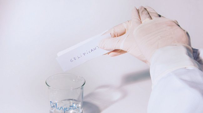 a hand in gloves holding a piece of paper with text