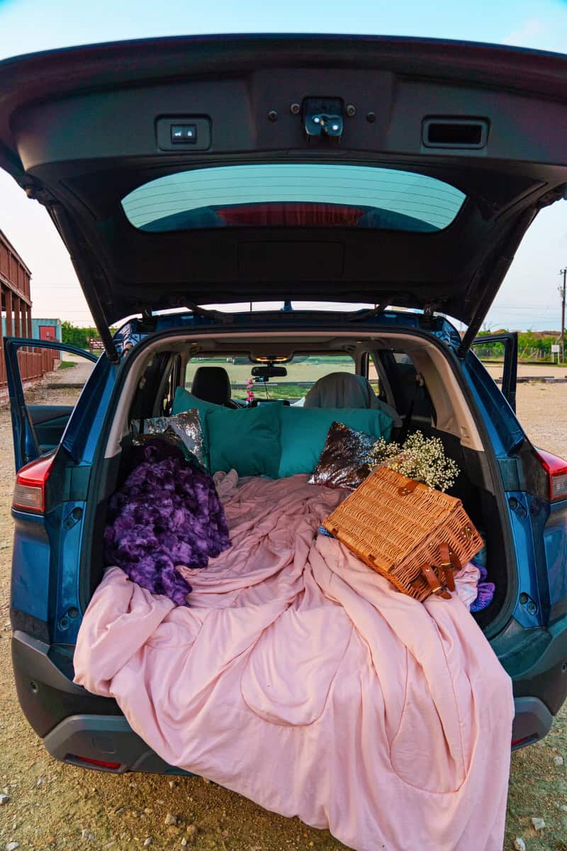 a car with a blanket and picnic basket in the back