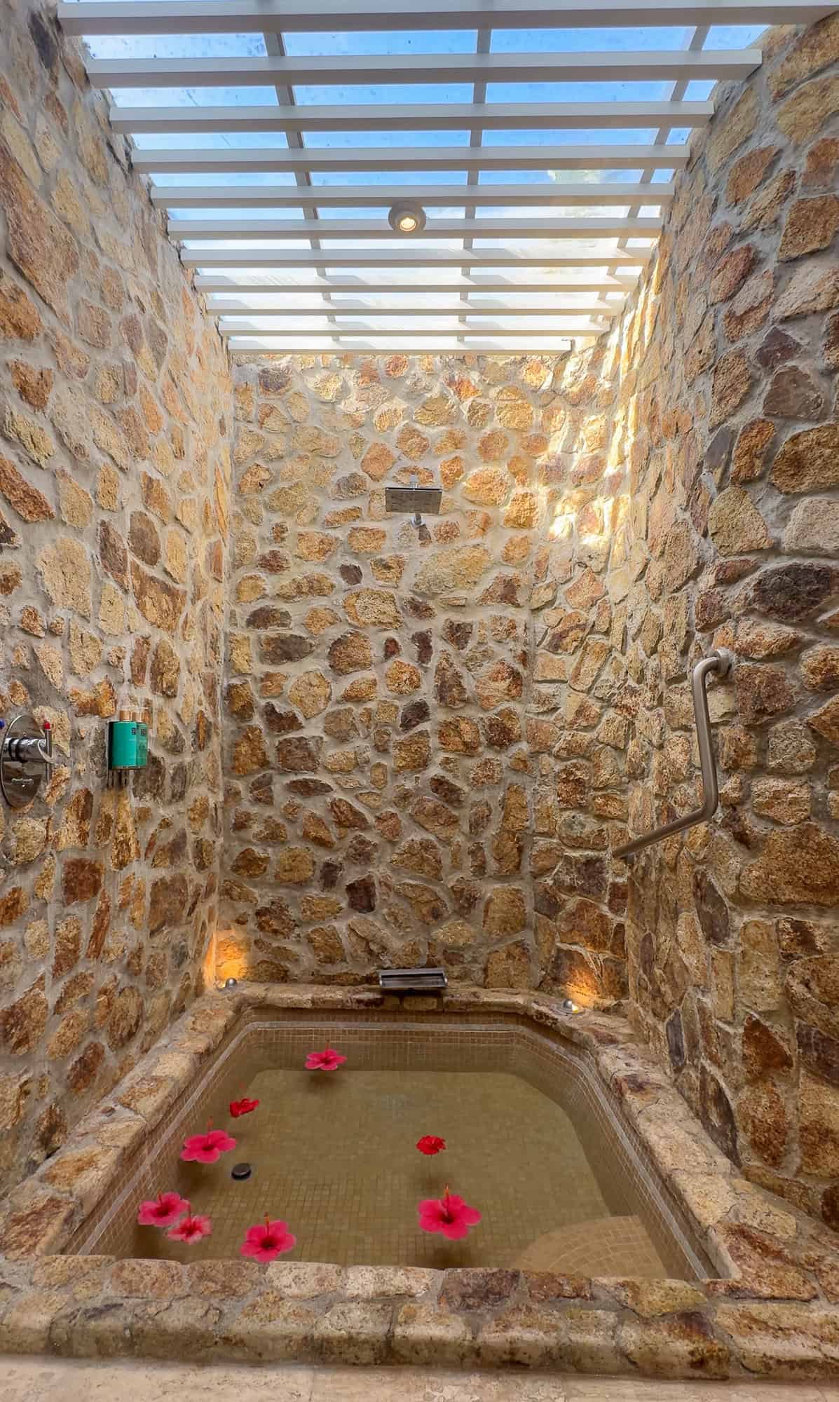 a stone shower with a bathtub and a handrail