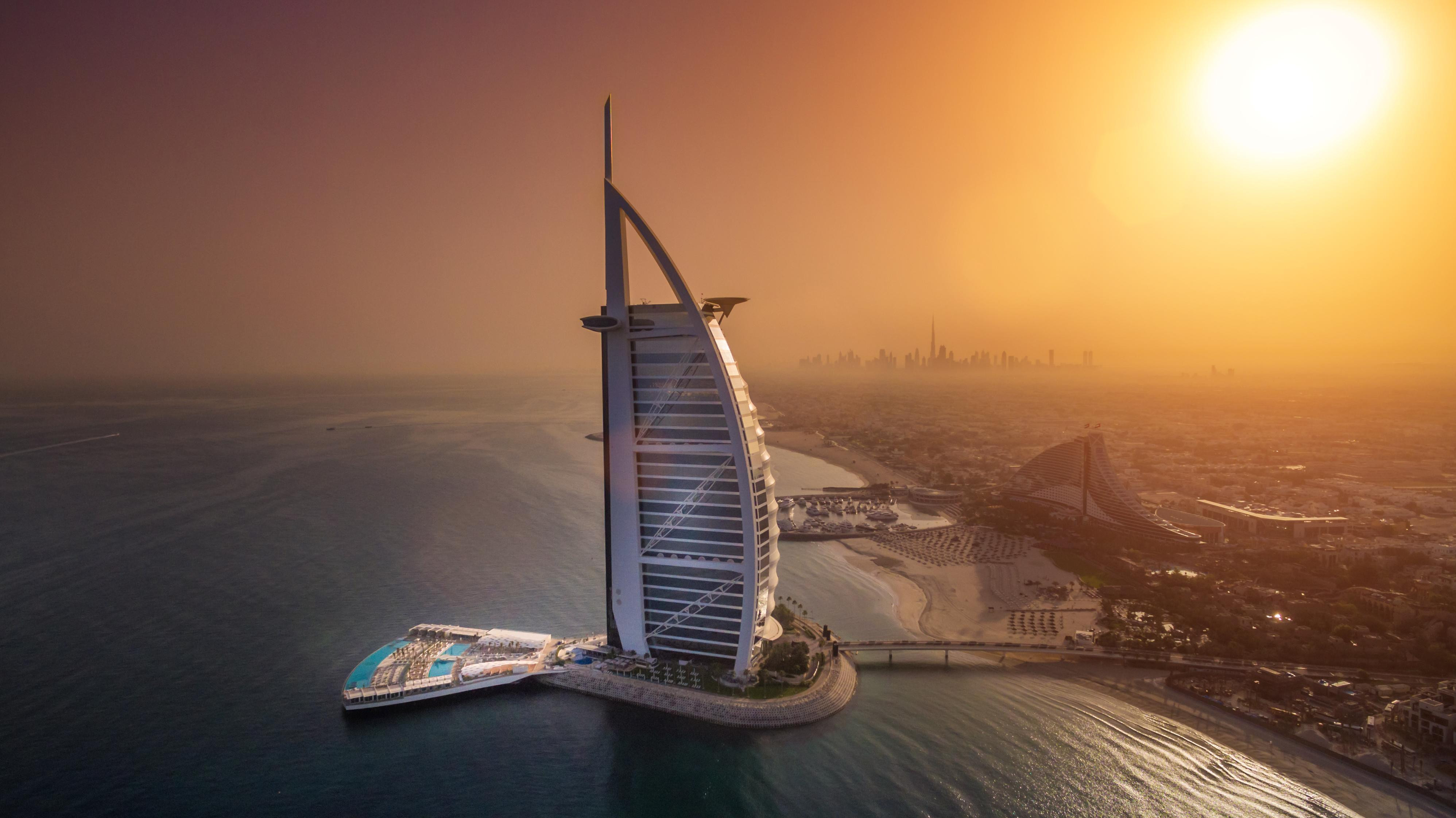 a tall building on a body of water with Burj Al Arab in the background