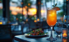 a glass of orange liquid and a plate of food on a table