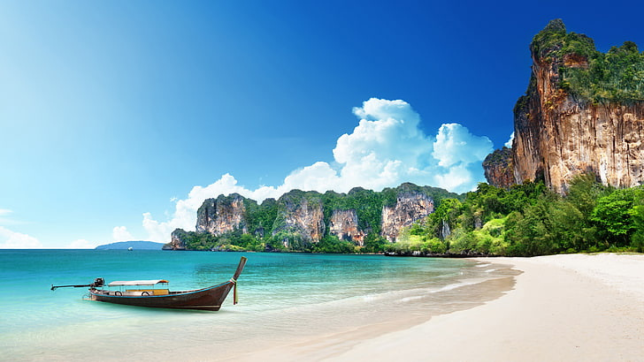 a boat on a beach with Railay Beach in the background