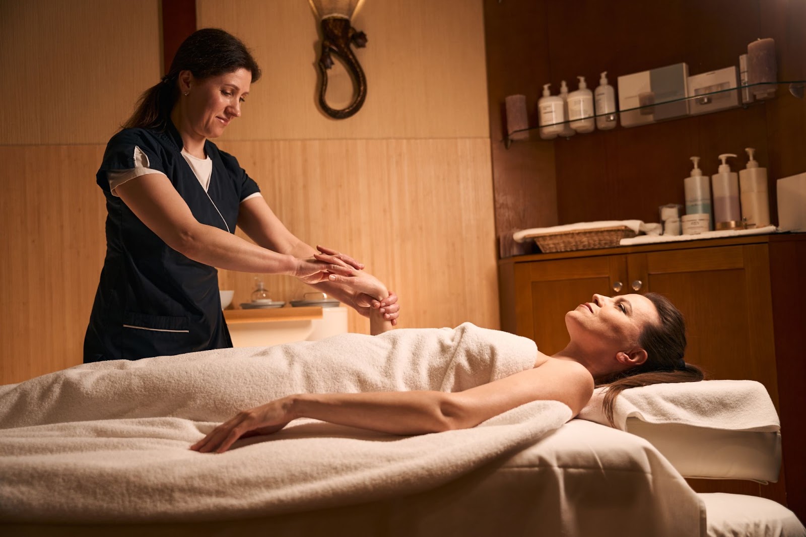 a woman lying on a bed with a woman in a massage room