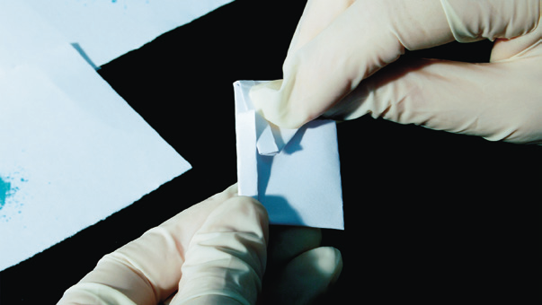 hands wearing gloves holding a small piece of paper