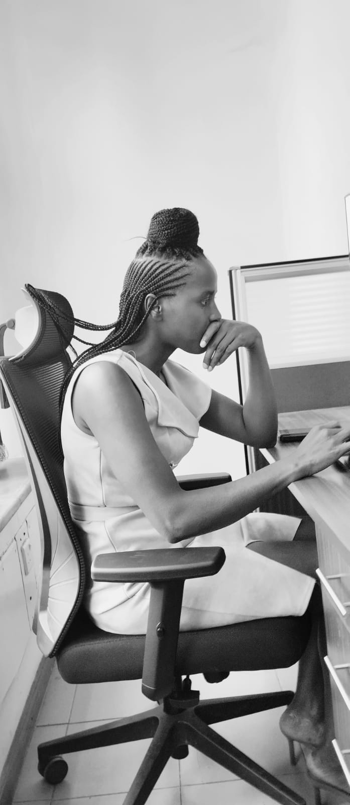 a woman sitting at a desk with her hand on her chin