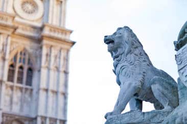 a statue of a lion in front of a clock tower