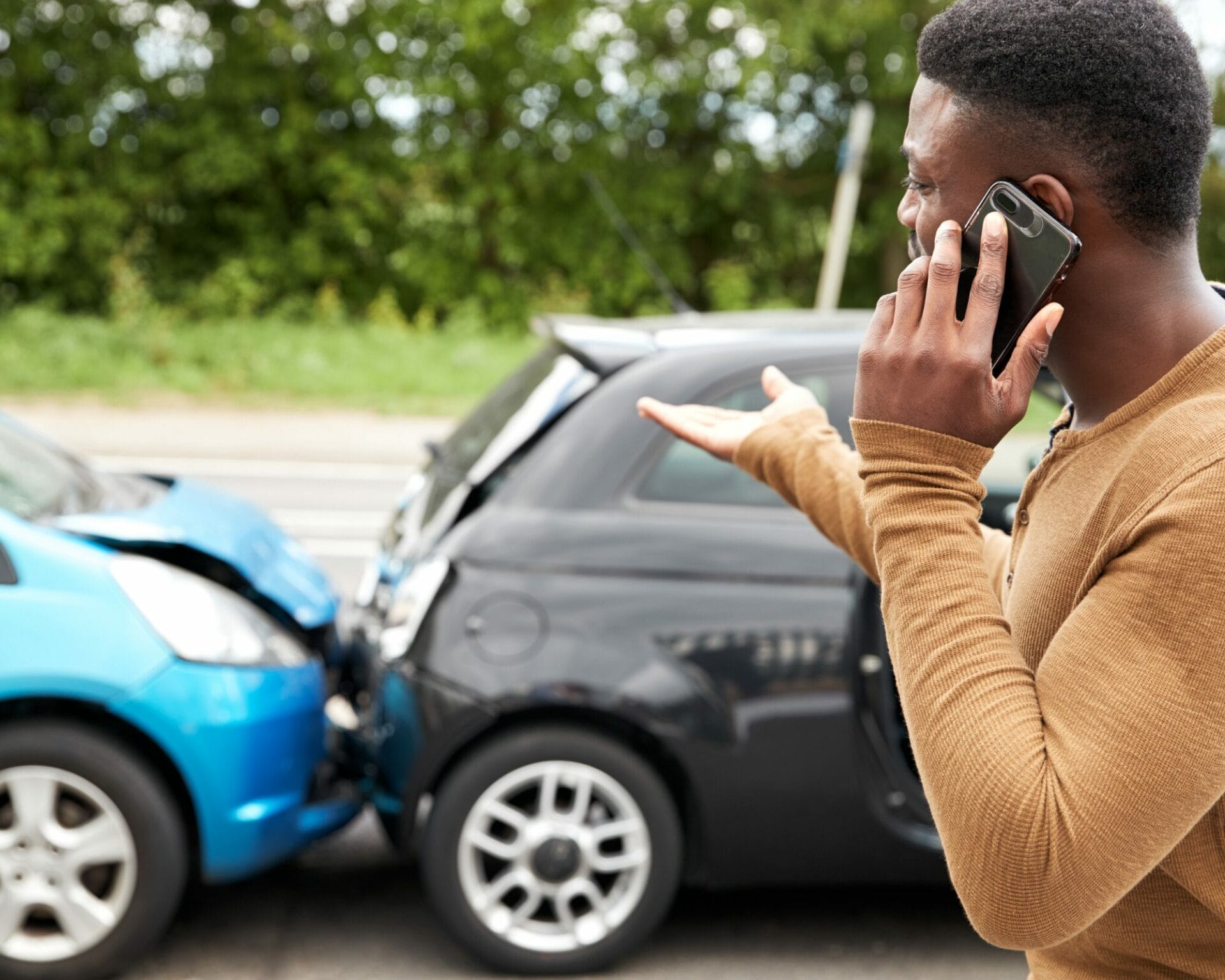 a man talking on a phone near a wrecked car