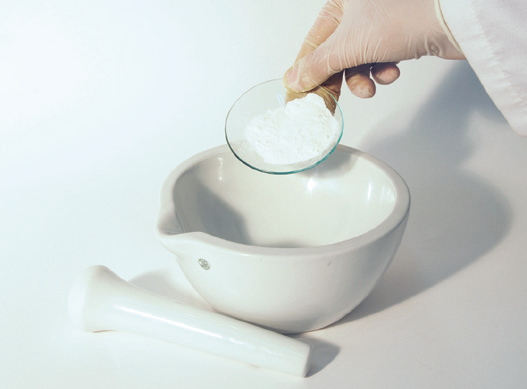 a person pouring powder into a mortar