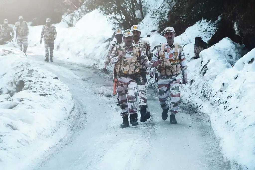 a group of men in camouflage walking on a snowy road