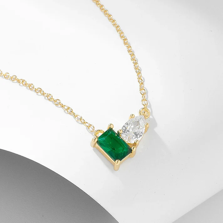 a gold necklace with a green stone and a diamond