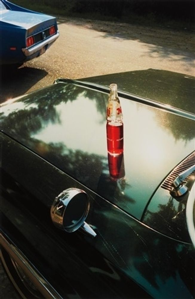 a bottle of red liquid on a car hood