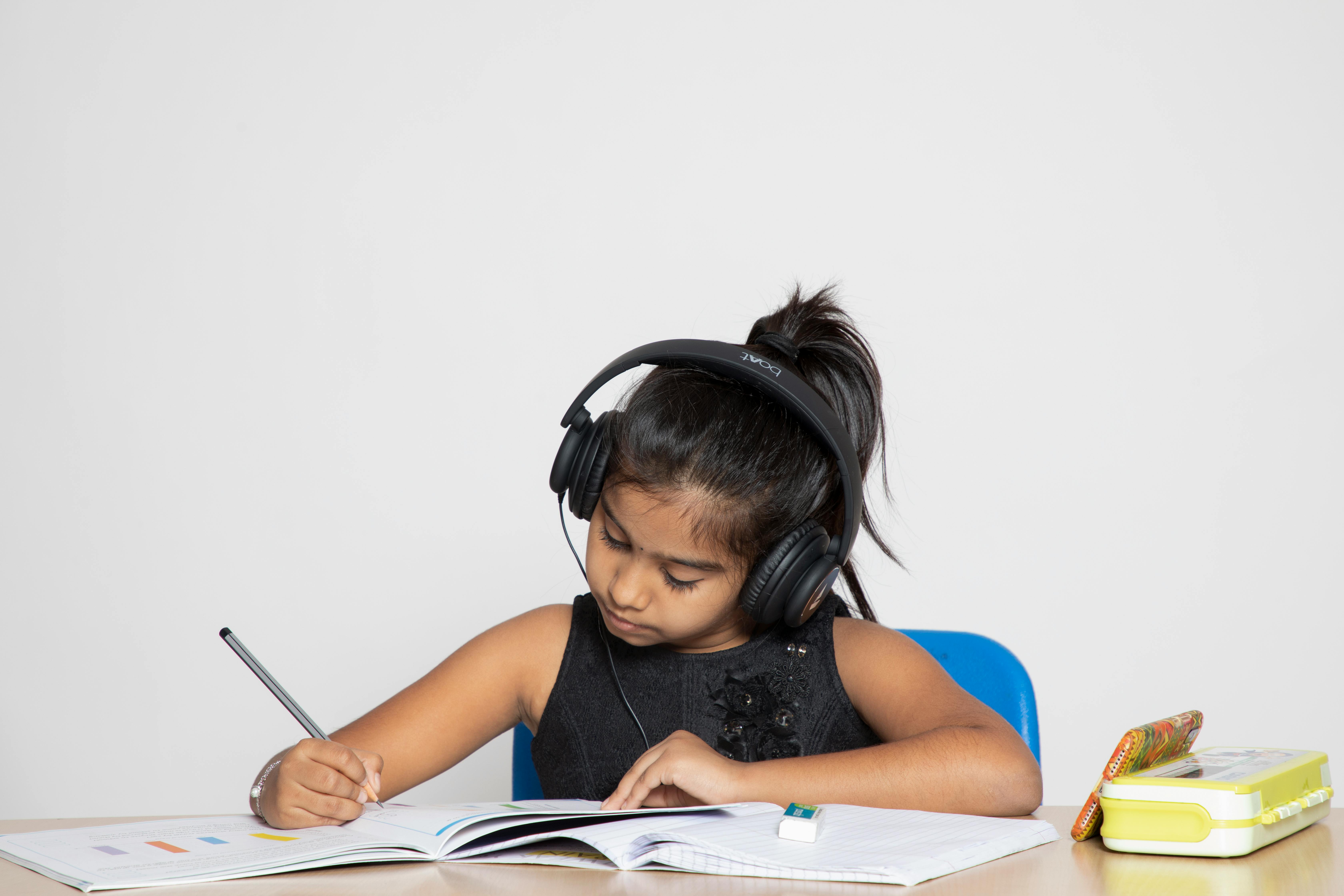 a girl wearing headphones and writing on a book