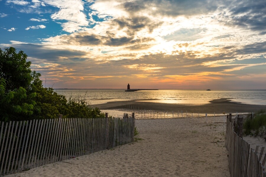 a beach with a fence and a lighthouse