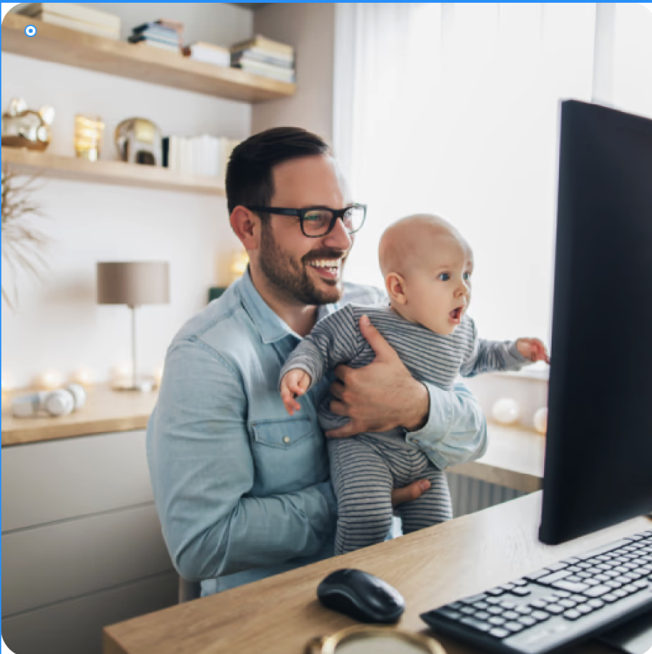 a man holding a baby and looking at a computer screen