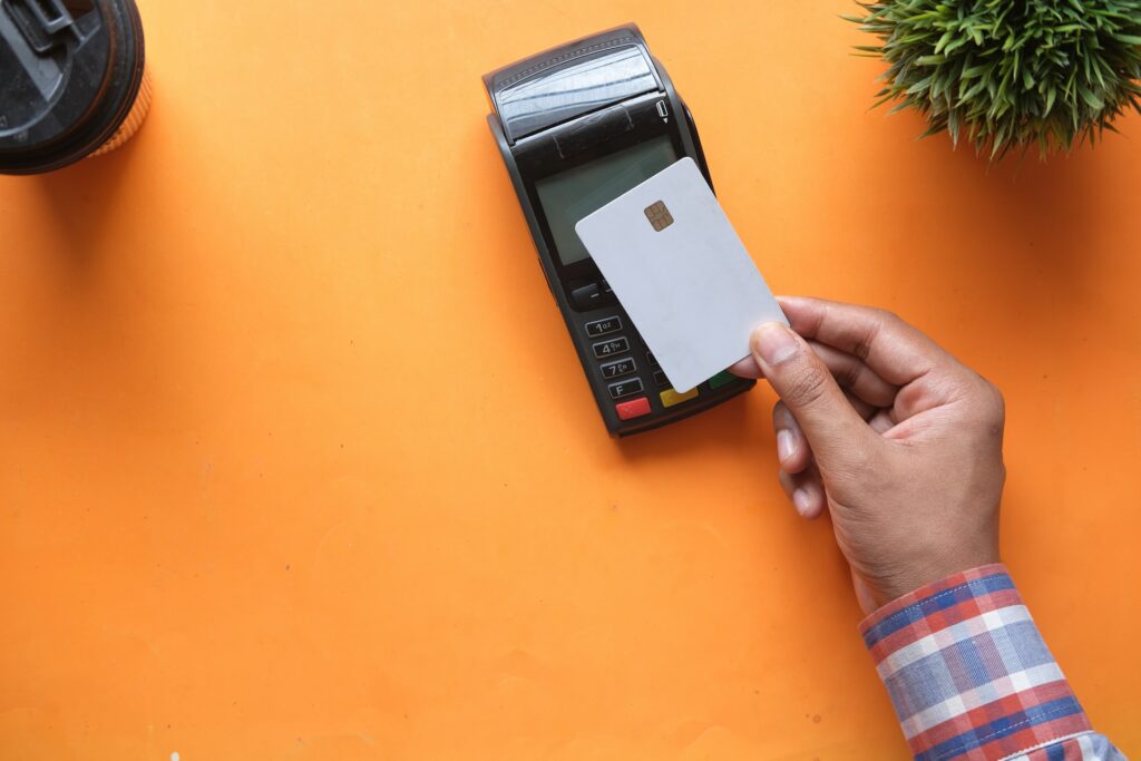 a person holding a credit card next to a credit card reader