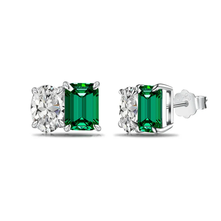 a pair of earrings with emerald stones