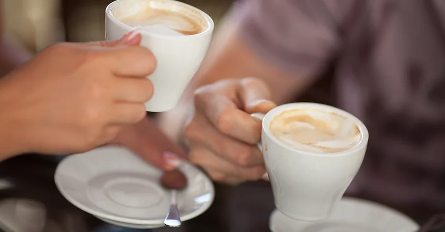 a close up of two hands holding coffee cups