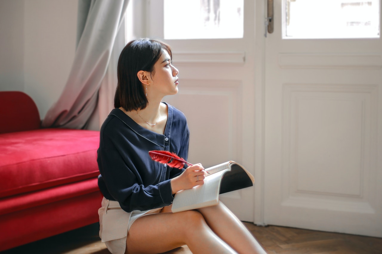 a woman sitting on a floor holding a book and a pen