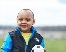 a young boy holding a football ball