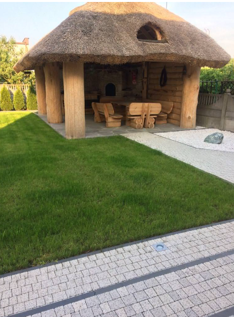 a wooden structure with a thatched roof and a grass lawn