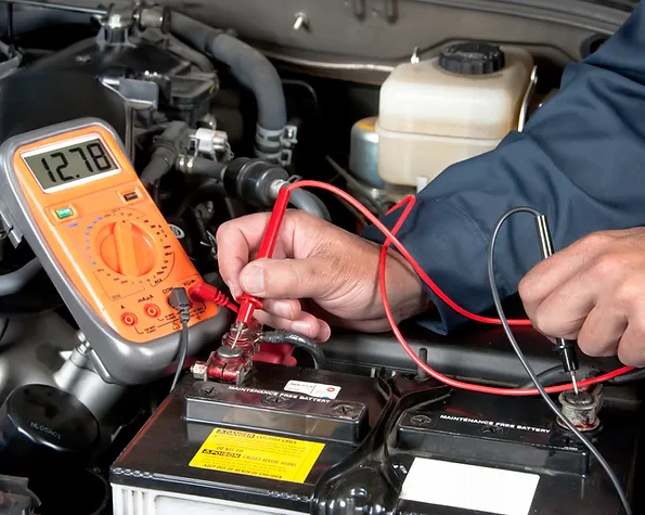a person using a multimeter to test a car battery