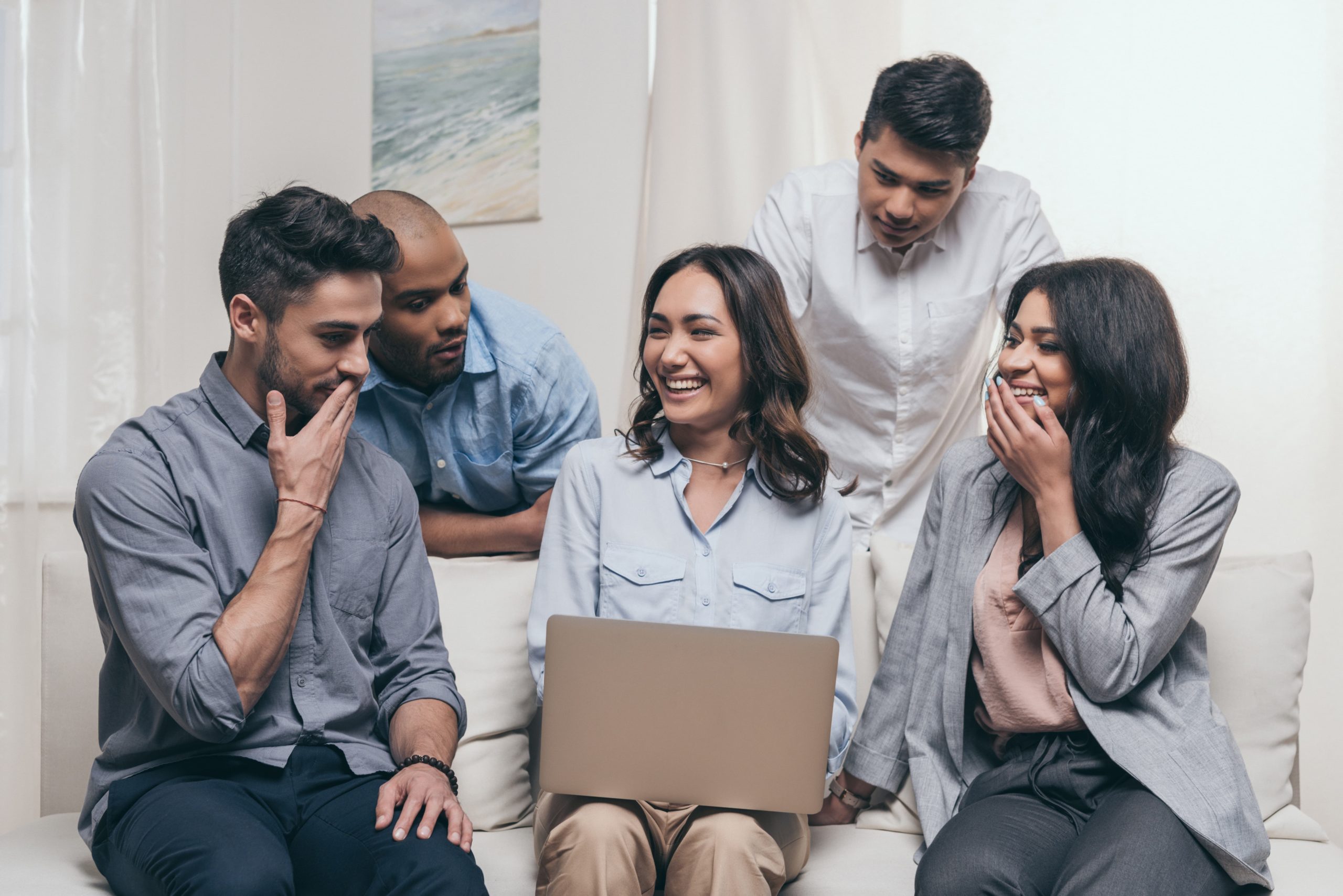 a group of people sitting on a couch looking at a laptop