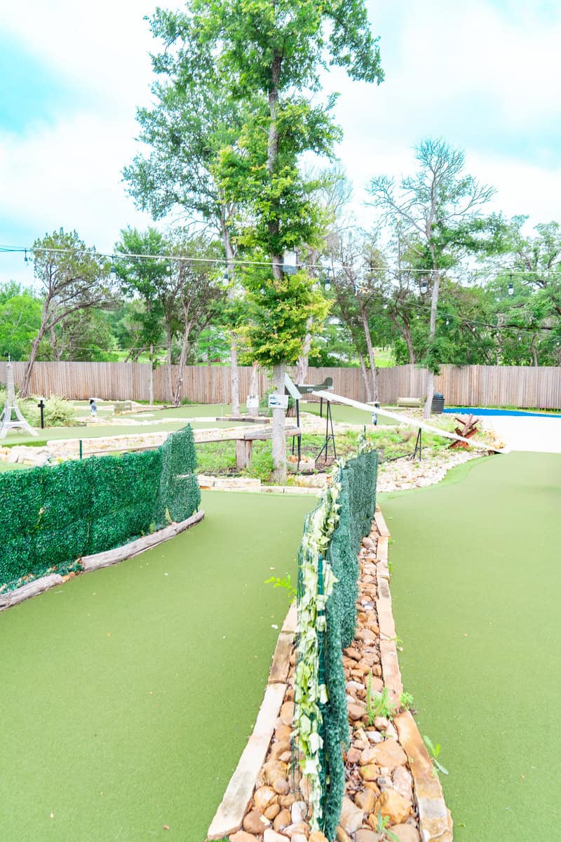 a miniature golf course with a tree and a fence