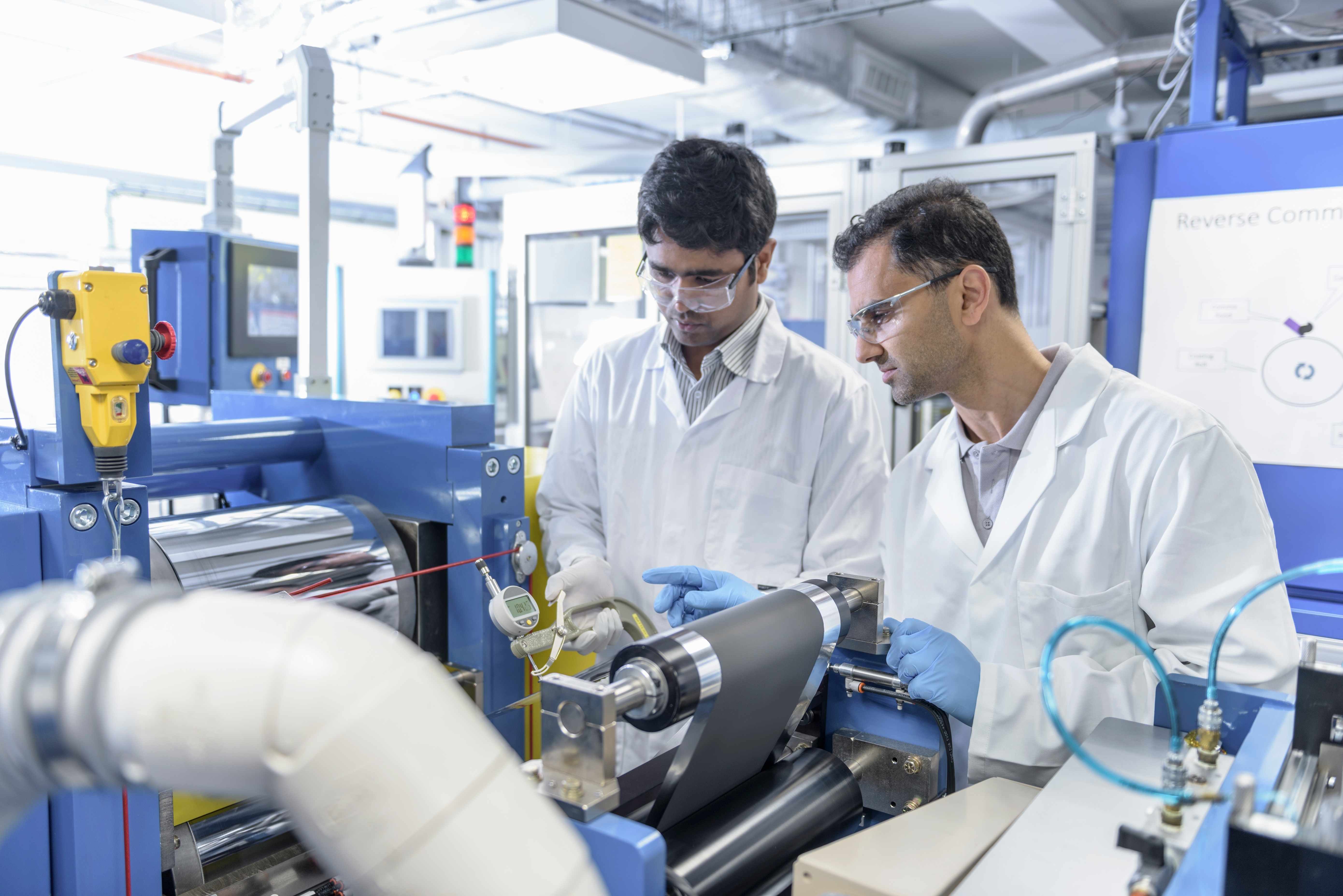 men in white coats and goggles looking at a machine