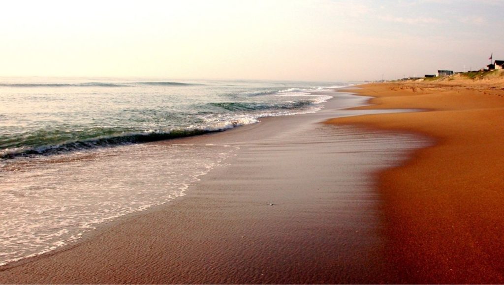 a sandy beach with waves crashing on the shore