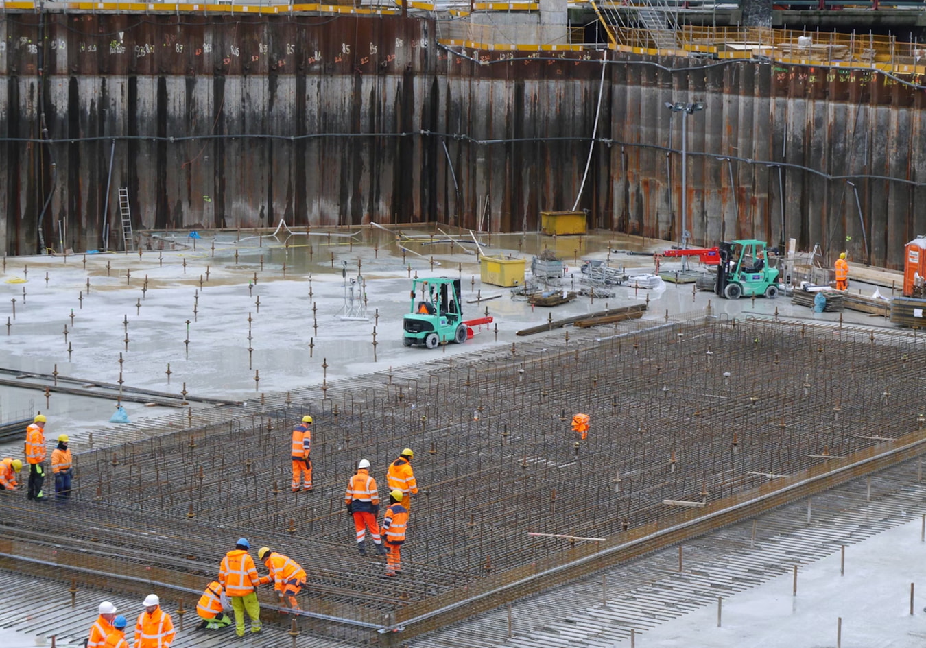 a group of people in orange vests standing on a construction site