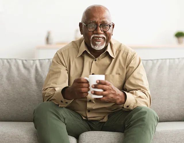 a man sitting on a couch holding a cup