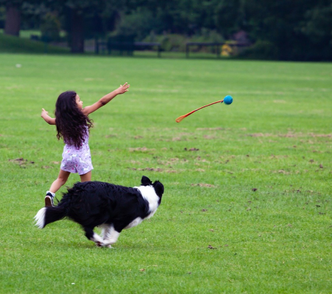a girl running with a ball and a stick in the air
