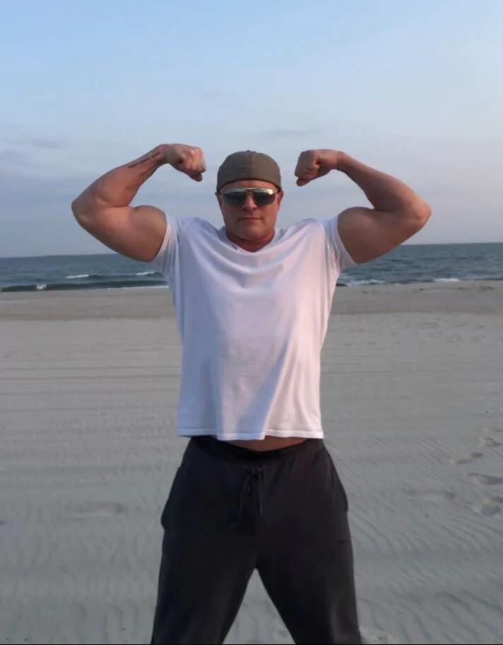 a man flexing his muscles on a beach