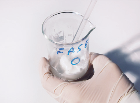 a hand holding a beaker with a tube and a straw