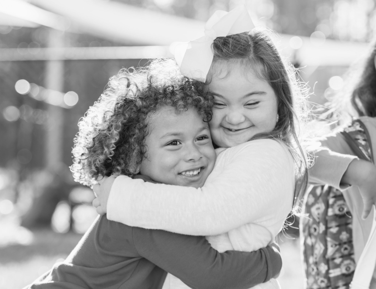 a black and white photo of two children hugging